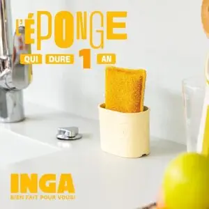 Une éponge durable de couleur jaune placée dans un porte-éponge de couleur crème avec le logo INGA, posé sur un plan de travail à côté d'un évier. Le texte en surimpression annonce 'L'éponge qui dure 1 an - INGA, bien fait pour vous!'